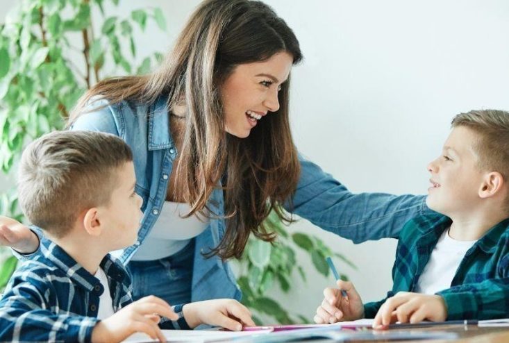 Ik legde bloemen op het graf van mijn tweeling, toen een jongen plotseling naar de grafsteen wees en zei: „Mam… die meisjes zitten bij mij in de klas.”